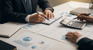 Mesa de reunião com documentos de análise financeira, calculadora e gráficos impressos, ângulo editorial diagonal